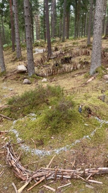 Winzige Wichtelhäuser aus Zweigen zwischen Bäumen im Wald