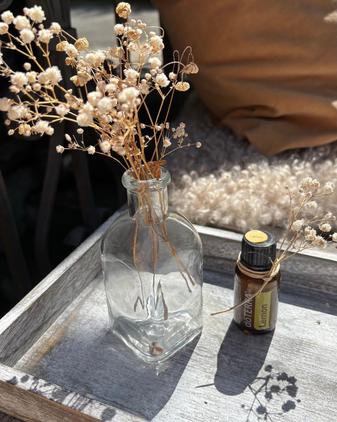 Ätherisches Öl neben Trockenblumen in einer Vase